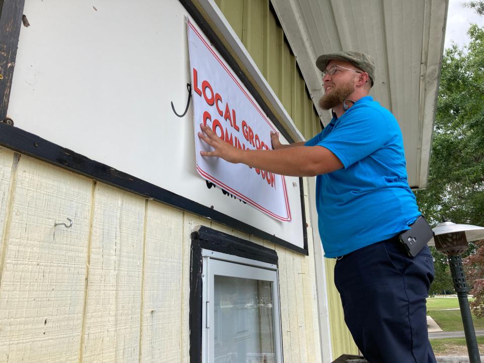 Jacob Towe hangs a sign announcing the new grocery store.
