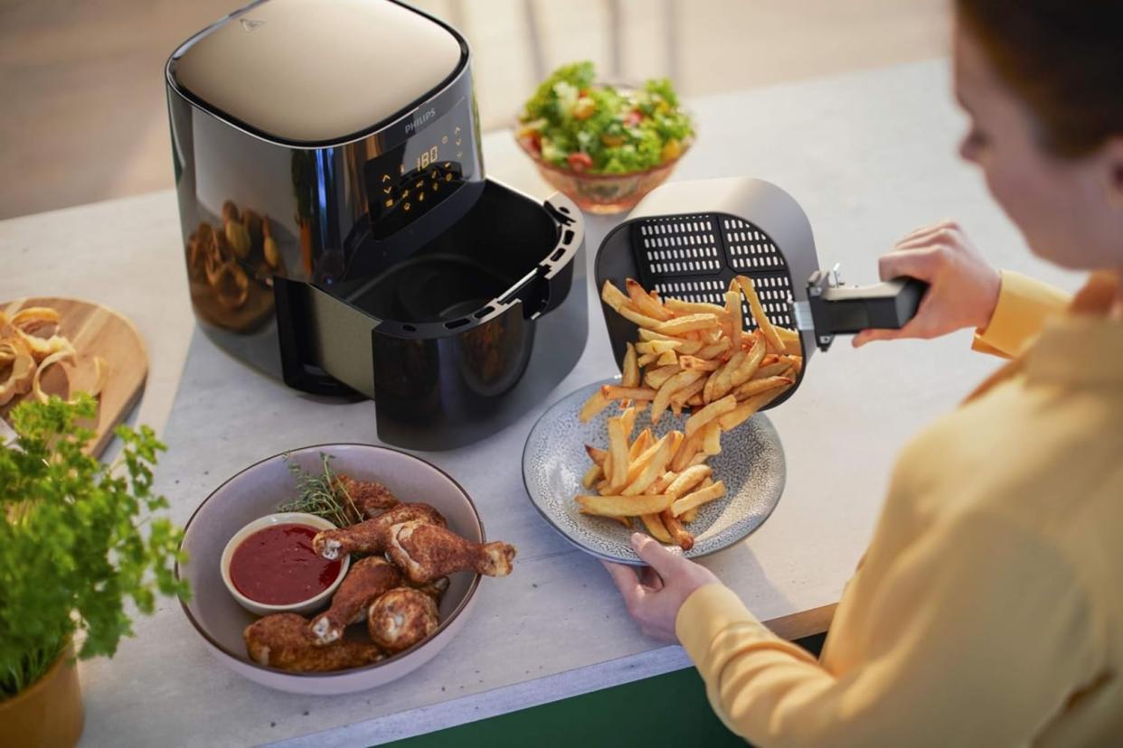 someone emptying the amazon air fryer basket filled with fries onto a plate