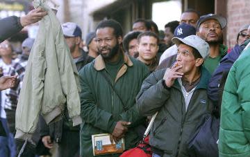 Homeless people stand in line for coats.