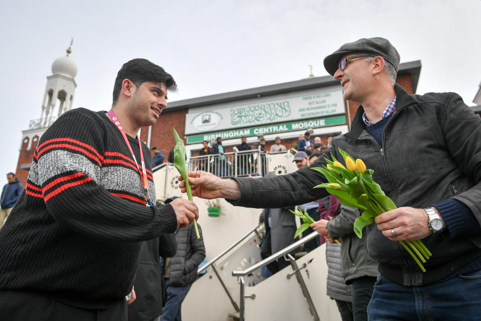 Christian James Lynch, from Riverside Church, hands out flowers to Muslims as they leave Birmingham Central Mosque as Friday prayers finish after the attack on the Mosque in Christchurch, New Zealand.