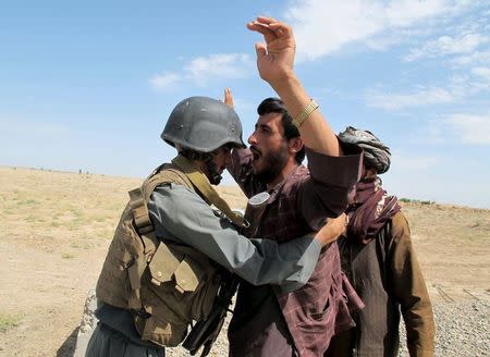 An Afghan policeman inspects a passenger at a checkpoint in Helmand province, Afghanistan July 30, 2015. REUTERS/Abdul Malik