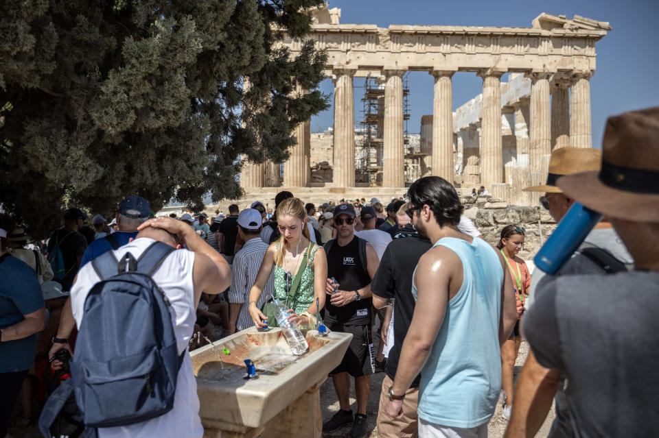 Tourists cool off at a water fountain during their visit to the Parthenon Temple in Athens, Greece (Angelos Tzortzinis / picture alliance via Getty Images)