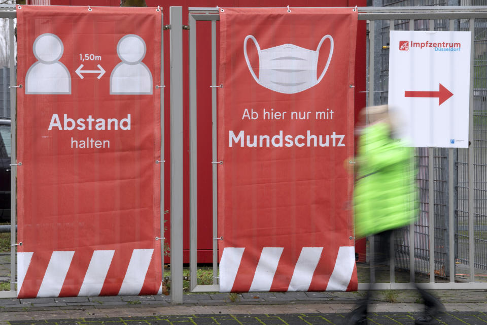 A person walks past an information sign for a vaccination center at a soccer stadium, home of German second division team Fortuna Duesseldorf, in Duesseldorf, Germany, Tuesday, Dec. 1, 2020. The German government is preparing to roll out a nationwide coronavirus vaccination program. (Federico Gambarini/dpa via AP)