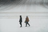 Pedestrians cross a snow covered street, Monday, Jan. 25, 2021, in downtown Des Moines, Iowa. A major winter storm is expected to blanket a large swath of the middle of the country with snow Monday and disrupt travel as more than a foot of snow falls in some areas. (AP Photo/Charlie Neibergall)