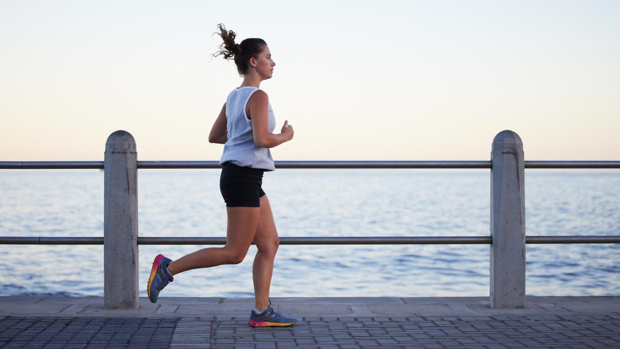  a photo of a woman running along a path next to the sea 