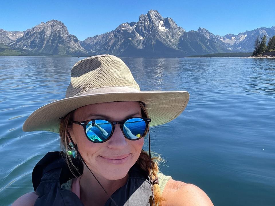 Emily taking a selfie on a boat in a lake with mountains in the background at Grand Teton National Park.