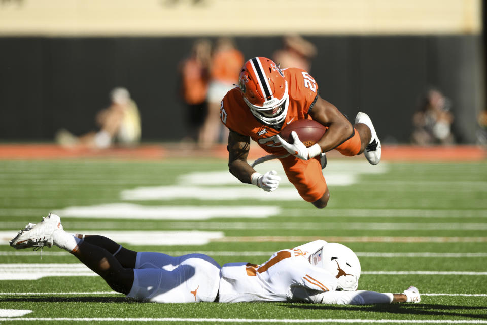 Oklahoma State running back Dominic Richardson (20) launches himself over Texas defensive back Anthony Cook, bottom, during the first half of an NCAA college football game Saturday, Oct. 22, 2022, in Stillwater, Okla. (AP Photo/Brody Schmidt)