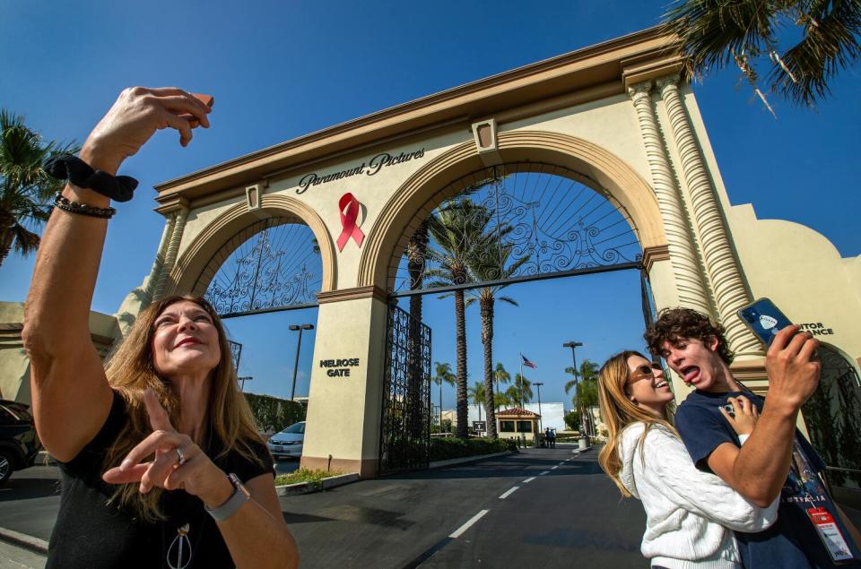 Three people taking selfies outside Paramount Studios.