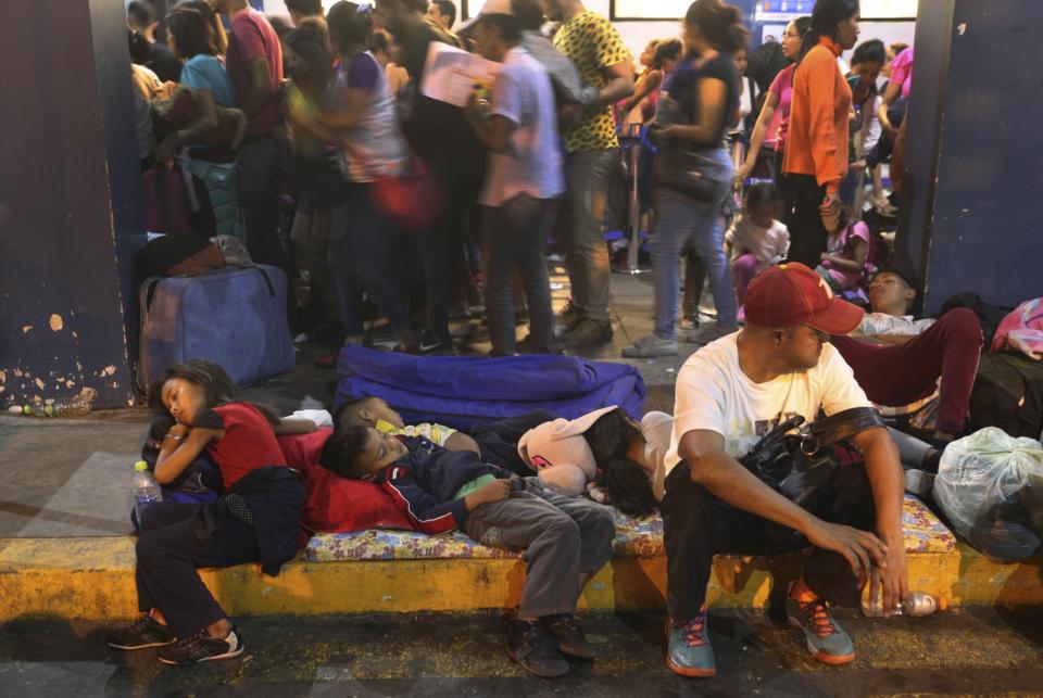 Venezuelan migrants rest while another group stands in line to enter am immigration office in Tumbes, Peru, Friday, June 14, 2019. Venezuelan citizens are rushing to enter Peru before the implementation of new entry requirements on migrants fleeing the crisis-wracked South American nation. (AP Photo/Martin Mejia)