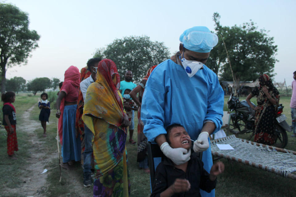 A health worker in personal protective equipment (PPE) collects a nasal swab.