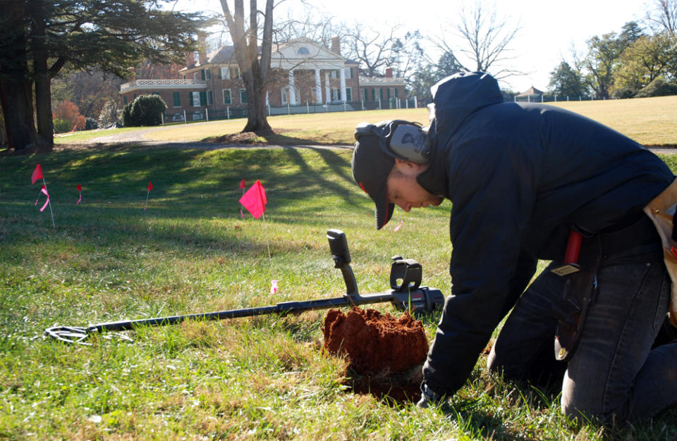 CORRECTS DATE OF PHOTO TO NOV. 14 NOT 15, AND LOCATION TO ORANGE, NOT MONPELIER, VA. - In this Thursday, Nov. 14, 2013, photo, Errol Belda, 26, of Bend, Ore., digs for an artifact after using a metal detector to survey land in the shadow of James Madison’s Montpelier, in Orange, Va. Archaeologists and metal-detecting hobbyists are teaming up to unearth the history that lies beneath the 2,650-acre Virginia estate dating back to the 18th century. The blips and beeps of the high-tech devices have helped rediscover historic sites the plantation belonging to the nation's fourth president, including slave quarters, Civil War camps, a blacksmith’s workshop and old tobacco barns. (AP Photo/Michael Felberbaum)