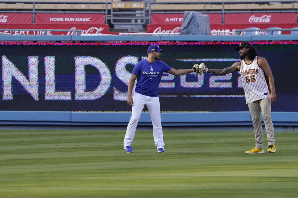 Los Angeles Dodgers' Blake Treinen, left, and San Diego Padres' Sean Manaea bump gloves during baseball practice Monday, Oct. 10, 2022, in Los Angeles for the National League division series. (AP Photo/Mark J. Terrill)