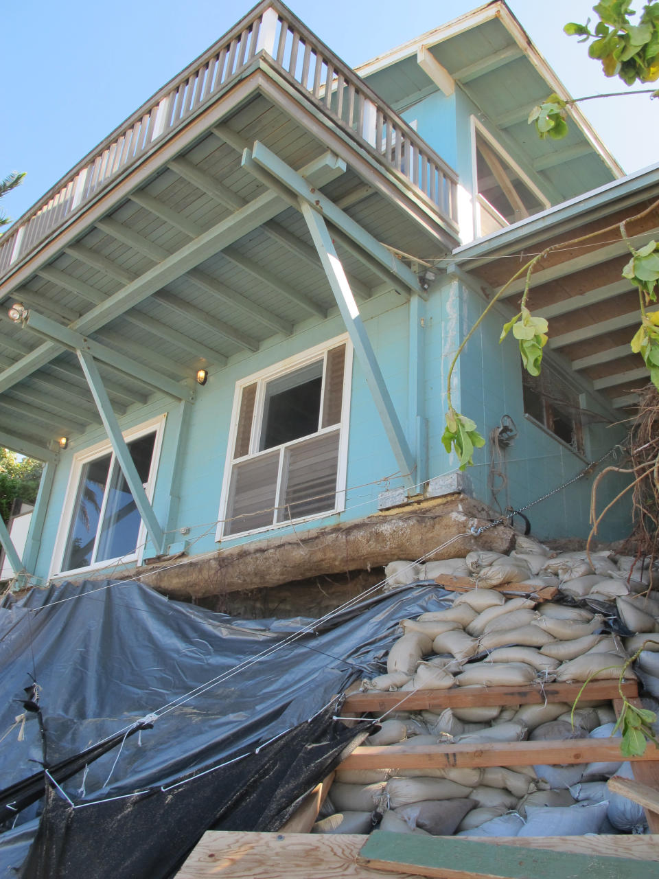 Sandbags are piled up in front of a house damaged by severe beach erosion in the Rocky Point neighborhood of Oahu's North Shore in Haleiwa, Hawaii on Tuesday, Dec. 31, 2013. Some property owners want to be able to install a seawall or something similar to protect their property, but scientists say doing so could lead the sand on the nearby coastline _ including Sunset Beach, home to some of the world’s top surfing contests _ to disappear. (AP Photo/Audrey McAvoy)