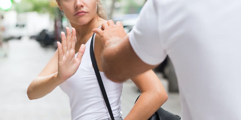 young woman looking upset by a stranger grabbing her shoulder in the street