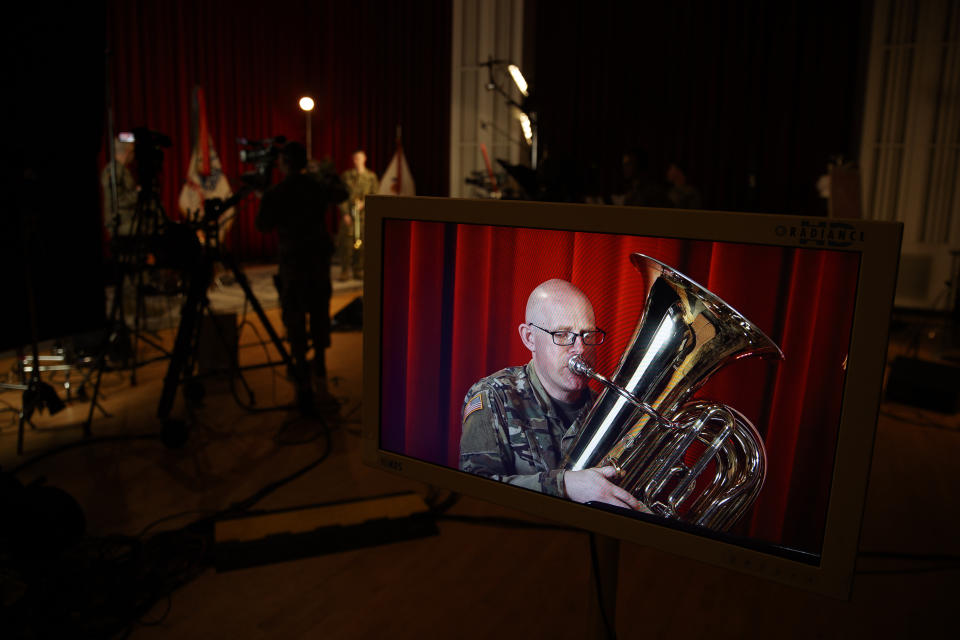 U.S. Army Field Band member Chief Warrant Officer 2 Kevin Pick is seen on a monitor as he plays his tuba during the rehearsal of their daily "We Stand Ready" virtual concert series at Fort George G. Meade in Fort Meade, Md., Wednesday, March 25, 2020. The Army Field Band's mission is to bring the military's story to the American people. And they're not letting the coronavirus get in the way. (AP Photo/Carolyn Kaster)