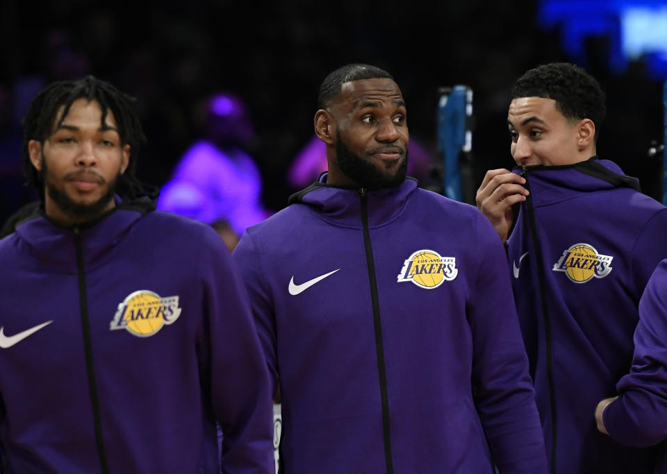 LeBron James, Brandon Ingram and Kyle Kuzma wear purple warmup hoodies before a game.