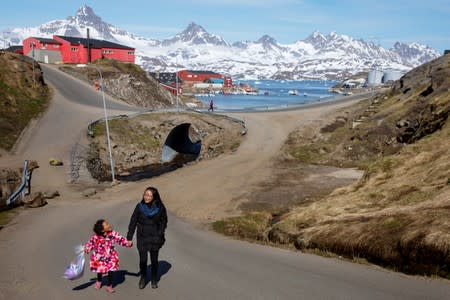 FILE PHOTO: A woman and child hold hands as they walk on the street in the town of Tasiilaq, Greenland