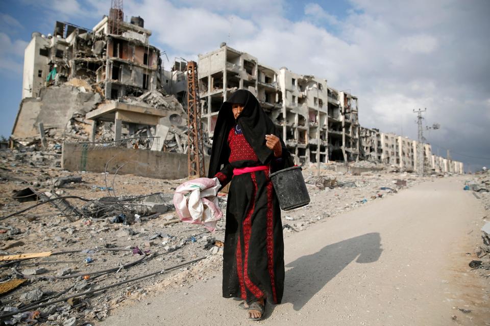 A Palestinian woman walks past buildings destroyed by what police said were Israeli air strikes and shelling in the town of Beit Lahiya in the northern Gaza Strip August 3, 2014