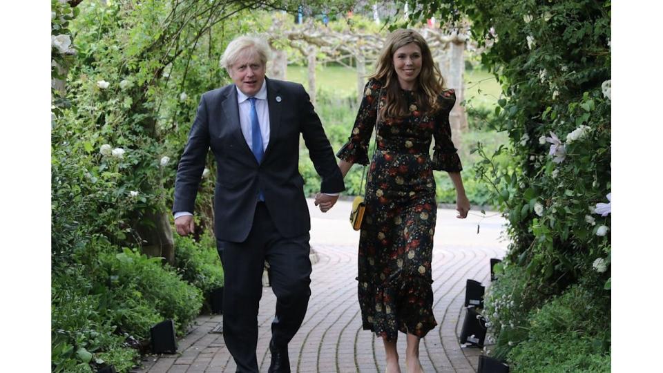  Boris Johnson and his wife Carrie Johnson walking through a floral arch in a garden