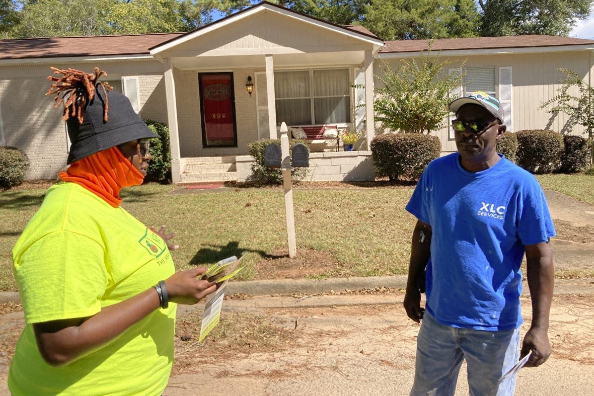 Erika Hardwick, left, a paid canvasser with the New Georgia Project Action Fund, talks to Joseph Peters about the upcoming election on Wednesday, Oct. 5, 2022 in Dawson, Ga. (AP Photo/Jeff Amy)