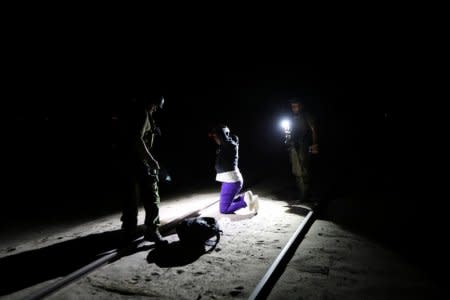 Migrant Yoniel Torres, 31, from Cuba is handcuffed after being detained by the police by a train line in a mined area of desert at the Chilean and Peruvian border in Arica, Chile, November 14, 2018.