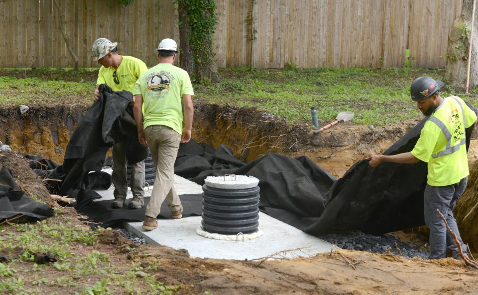 Robert B. Our workers Dan Ulmer, left, Niya Bryce and Bill Quigley start to backfill a new septic system they installed in Hyannis Thursday.