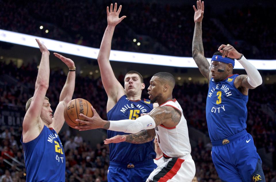 Portland Trail Blazers guard Damian Lillard, center, passes the ball away from Denver Nuggets forward Mason Plumlee, left, center Nikola Jokic, second from left, and forward Torrey Craig, right, during overtime of Game 3 of an NBA basketball second-round playoff series Friday, May 3, 2019, in Portland, Ore. (AP Photo/Craig Mitchelldyer)