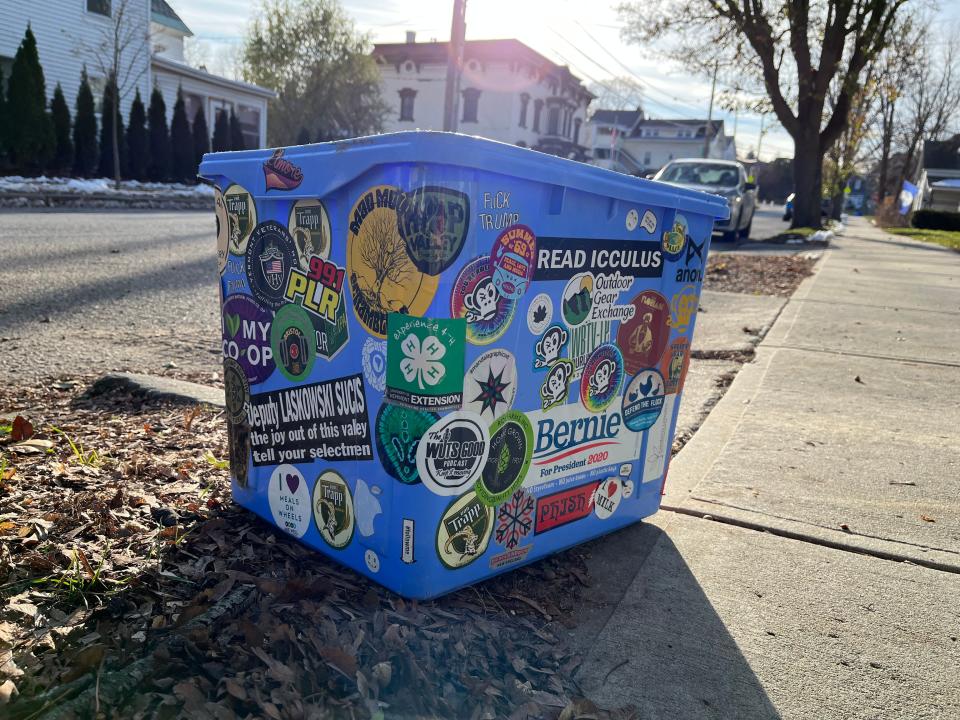 A decorated blue recycling bin sits on the curb on a residential street in Burlington. Thousands of households still use the lid-less blue bins which will soon be completely phased out with new city rules.
