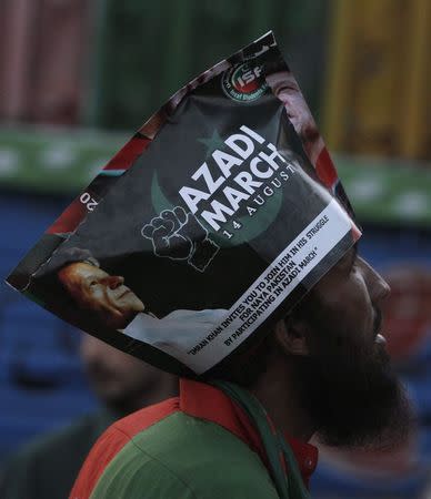 A supporter of chairman of the Pakistan Tehreek-e-Insaf (PTI) political party Imran Khan wears a poster on his head as he listens to his speech a Freedom March in Islamabad August 20, 2014. REUTERS/Faisal Mahmood