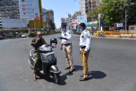 Police personnel check the details of a scooter rider during a nationwide one-day Janata (civil) curfew imposed as a preventive measure against the COVID-19 coronavirus, in Mumbai on March 22, 2020. - Nearly one billion people around the world were confined to their homes, as the coronavirus death toll crossed 13,000 and factories were shut in worst-hit Italy after another single-day fatalities record. (Photo by INDRANIL MUKHERJEE / AFP) (Photo by INDRANIL MUKHERJEE/AFP via Getty Images)