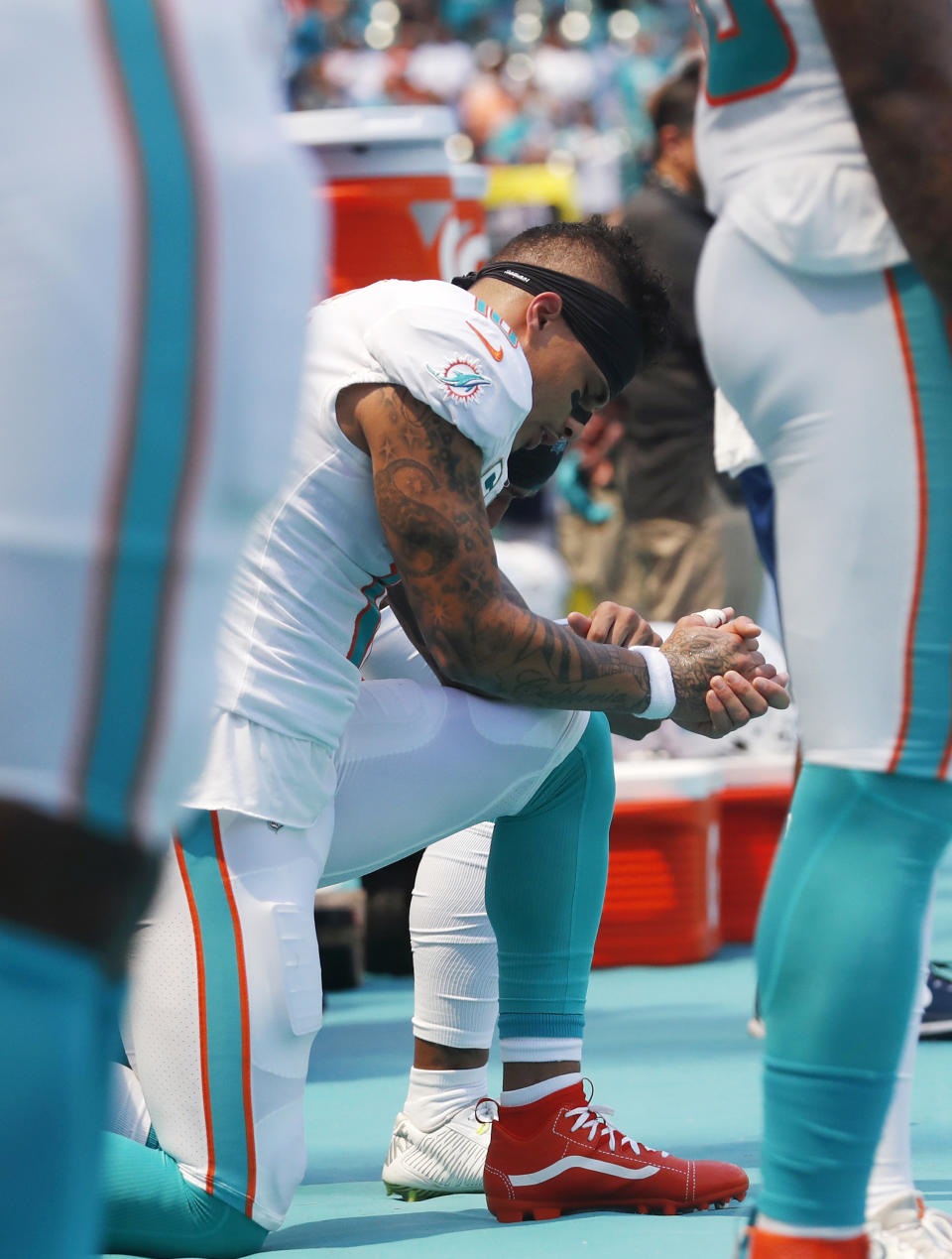 Miami Dolphins wide receiver Kenny Stills and wide receiver Albert Wilson, obscured, take a knee during the singing of the national anthem before an NFL football game against the Oakland Raiders, Sunday, Sept. 23, 2018, in Miami Gardens, Fla. (AP Photo/Brynn Anderson)