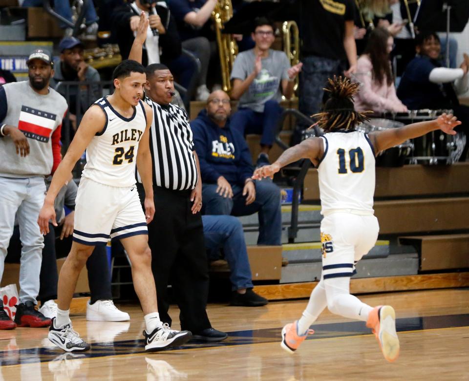 South Bend Riley junior Marvin Schindler (10) goes to celebrate with senior Mancell Hill (24) after Hill made a '3' at the end of the first half of a boys basketball game against South Bend Washington Thursday, Feb. 1, 2024, at Riley High School.