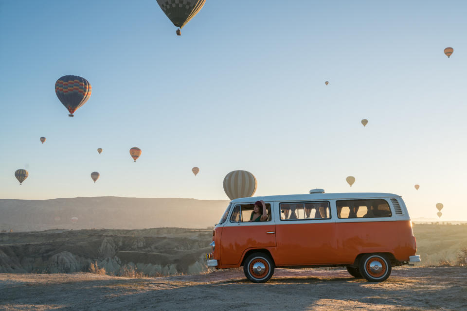 Heißluftballons am Himmel über Kappadokien in der Türkei, Bulli von VW im Vordergrund 