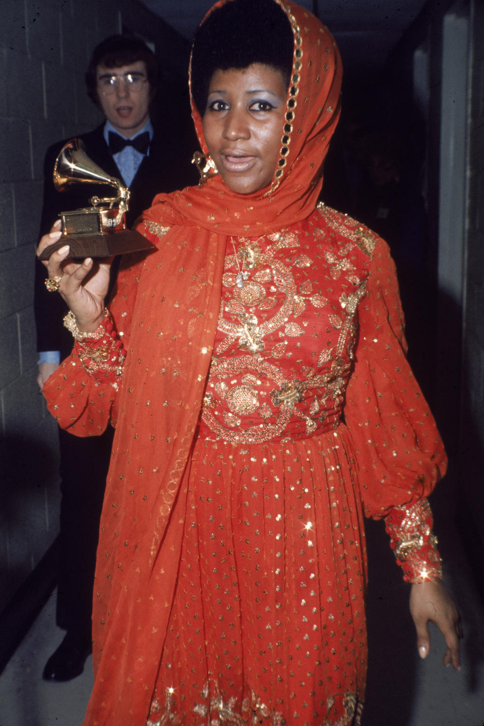 Standing backstage wearing a gold embroidered gown and holding a Grammy Award, circa 1970.