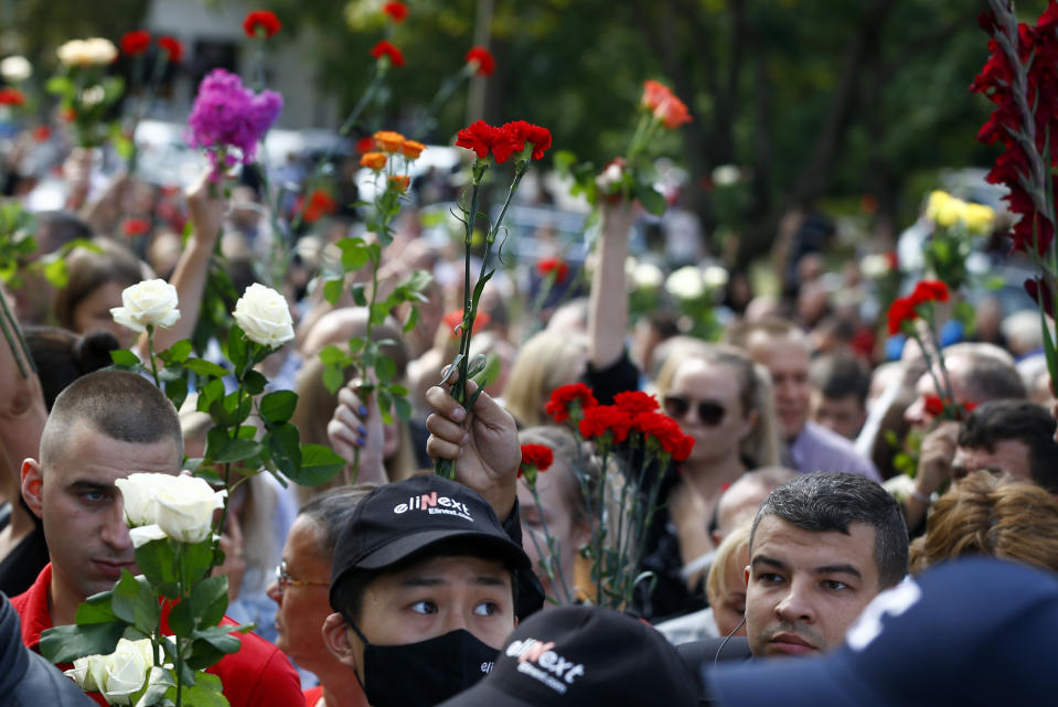 People wave flowers at the farewell hall during the funeral of Alexander Taraikovsky who died amid clashes protesting the election results, in Minsk, Belarus, Saturday, Aug. 15, 2020. Taraikovsky died Monday as demonstrators roiled the streets of the capital Minsk, denouncing official figures showing that authoritarian President Alexander Lukashenko, in power since 1994, had won a sixth term in office. (AP Photo/Sergei Grits)