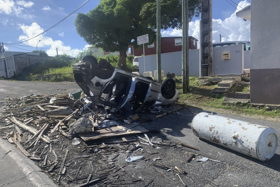 An overturned car is pictured in a s street of Le Gosier, Guadeloupe island, Sunday, Nov.21, 2021. French authorities are sending police special forces to the Caribbean island of Guadeloupe, an overseas territory of France, as protests over COVID-19 restrictions erupted into rioting. The protests have been called for by trade unions to denounce the COVID-19 health pass that is required to access restaurants and cafes, cultural venues, sport arenas and long-distance travel. (AP Photo/Elodie Soupama)