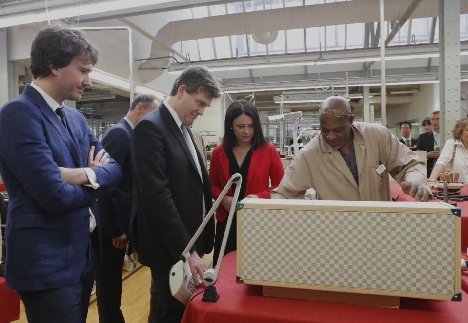 French Minister for Industrial Recovery Arnaud Montebourg, 2nd left, with Trade and Tourism deputy Minister Sylvia Pinel reacts with LVMH workers during a visit of "Particular operation days" in LVMH, the world's largest luxury company at the factory of Vuitton, in Asnieres north of Paris Saturday June 15, 2013. At left, LVMH member of the board of directors Antoine Arnault looks one. (AP Photo/Jacques Brinon)