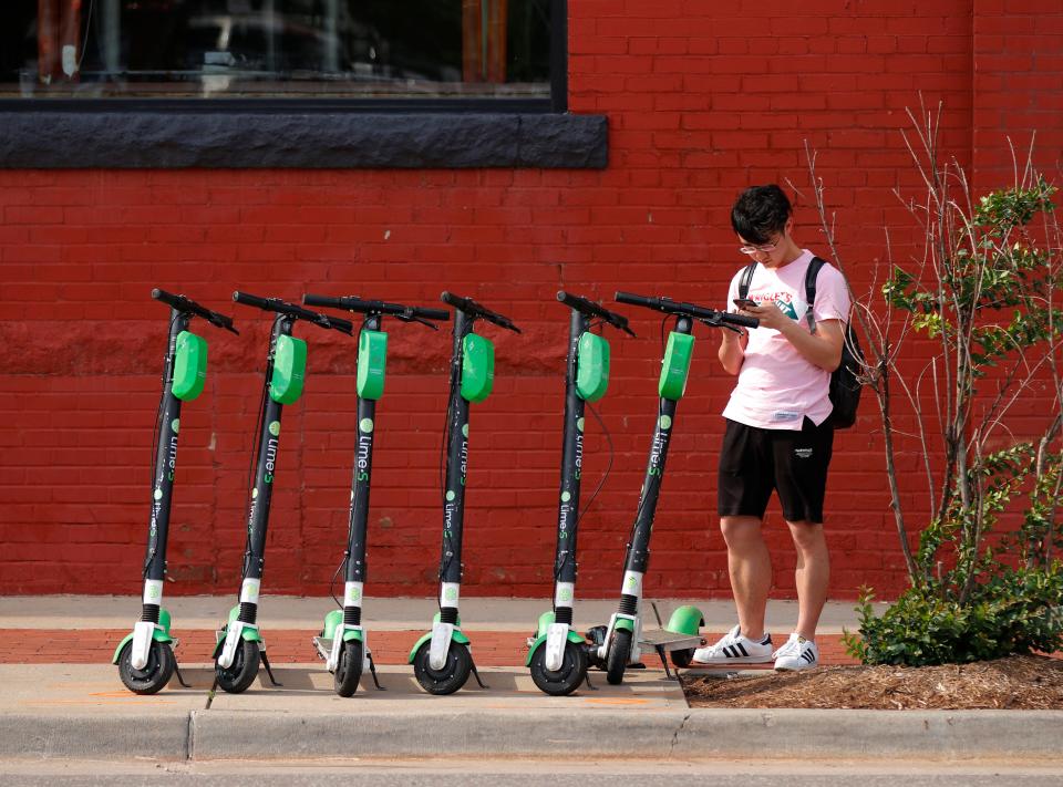 A man unlocks a scooter in Bricktown on Friday, June 14, 2019.