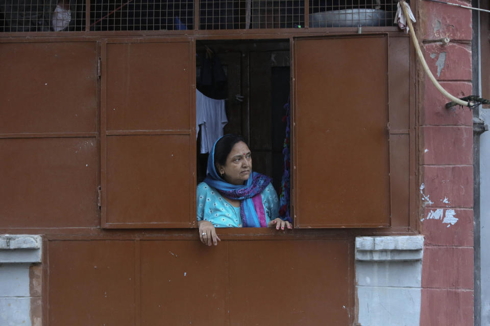 In this Aug. 23, 2019, photo, a Kashmiri Hindu woman looks from inside her residence at the Jagti migrant camp in Jammu, India. Tens of thousands of Kashmiri Hindus fled the restive region nearly 30 years ago, and the ghost of insurgency and their mass exodus still haunts them. They celebrated after India’s Hindu nationalist-led government stripped political autonomy from its part of Muslim-majority Kashmir on Aug. 5. Kashmiri Hindus view it as a step toward justice and possible return to their homeland. But many are still wary of returning. (AP Photo/Channi Anand)