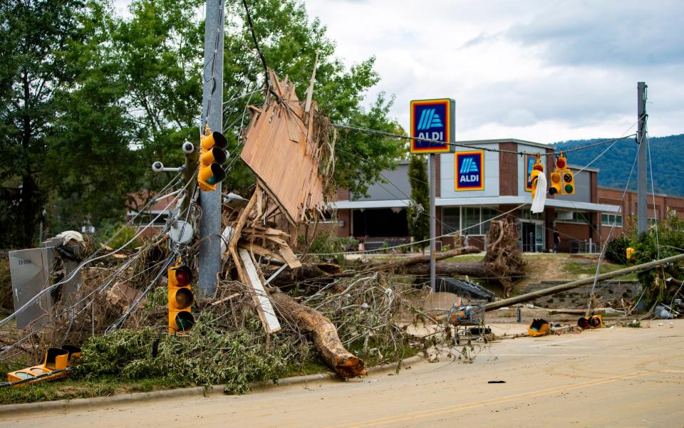 Debris piles up along Swannanoa River Road in downtown Asheville Sunday afternoon.