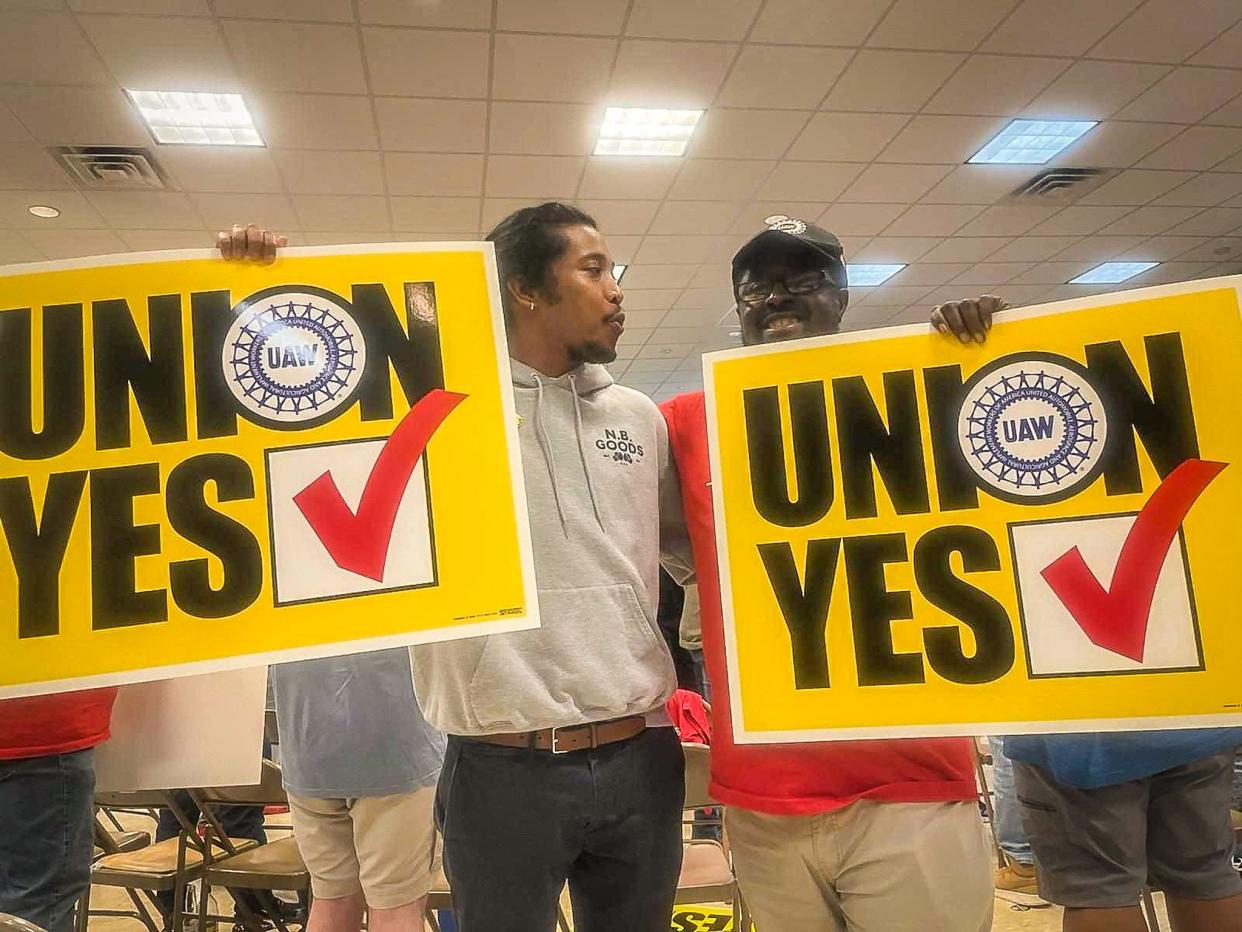 Frank Jennings (right), who has worked in the body shop at Chattanooga's Volkswagen plant for seven years, celebrates a vote Friday evening in favor of unionization as he stands with signs next to Rep. Justin Jones, D-Nashville.