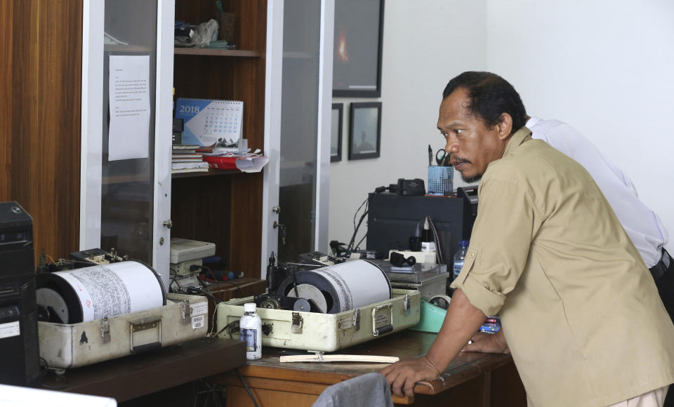 An official looks a seismograph at an observation post near a recent volcanic eruption in Carita, Indonesia, Thursday, Dec. 27, 2018. Indonesia has widened the no-go zone around an island volcano that triggered a tsunami on the weekend, killing hundreds of people in Sumatra and Java. (AP Photo/Achmad Ibrahim)