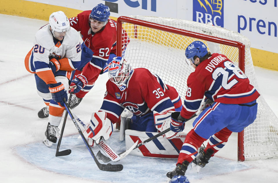 New York Islanders' Hudson Fasching (20) tries to put the puck past Montreal Canadiens goaltender Sam Montembeault (35) as Canadiens' Justin Barron (52) and Christian Dvorak (28) defend during the third period of an NHL hockey match in Montreal, Saturday, Dec. 16, 2023. (Graham Hughes/The Canadian Press via AP)