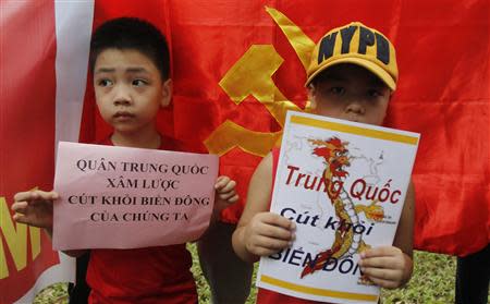 Boys hold placards which read "Chinese invaders, get out of the East Sea (South China Sea)" (L) and "China get out, East Sea", in front of the Chinese embassy during an anti-China protest in Hanoi May 11, 2014. REUTERS/Kham