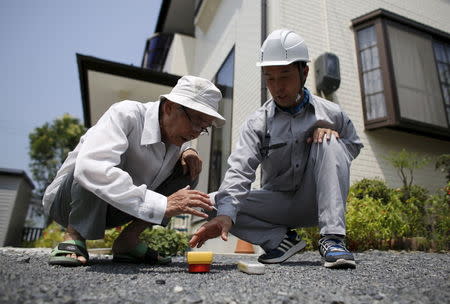 Yoshiteru Kohata (L), a 86-year-old Nagasaki atomic bombing survivor and retired school teacher, who returned to his home region of Fukushima after World War Two, looks at a Geiger counter to check the radiation level with an examiner in the garden at his home in the town of Miharu, Fukushima Prefecture, Japan, July 31, 2015.REUTERS/Toru Hanai