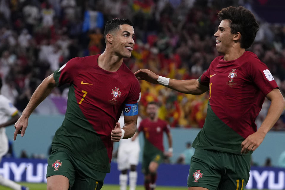 Portugal's Cristiano Ronaldo, left, celebrates with teammate Joao Felix after scoring from the penalty spot his side's opening goal against Ghana during a World Cup group H soccer match at the Stadium 974 in Doha, Qatar, Thursday, Nov. 24, 2022. (AP Photo/Manu Fernandez)