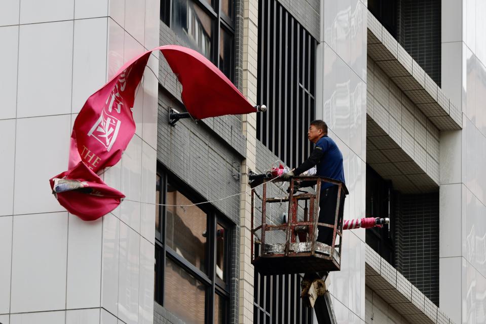 A Taiwanese worker folds advertising banners outside a building in anticipation for Typhoon Krathon in New Taipei City, Taiwan (EPA)