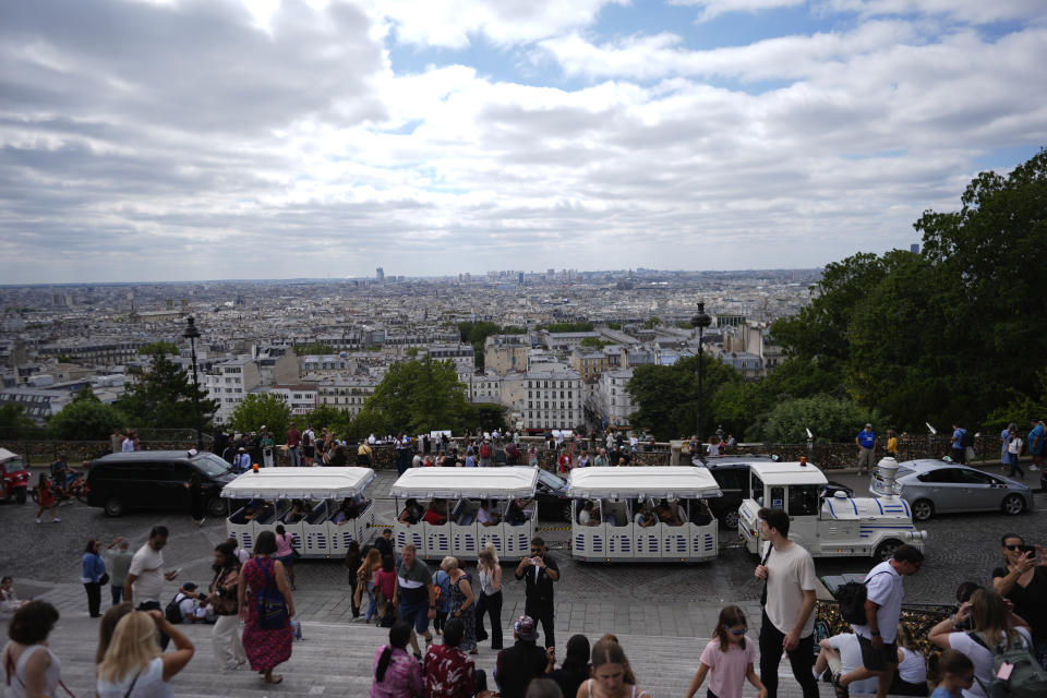 A tourist train passes as people visit the steps below Sacre Coeur of Montmartre Basilica, ahead of the 2024 Summer Olympics, Monday, July 22, 2024, in Paris, France. (AP Photo/Rebecca Blackwell)