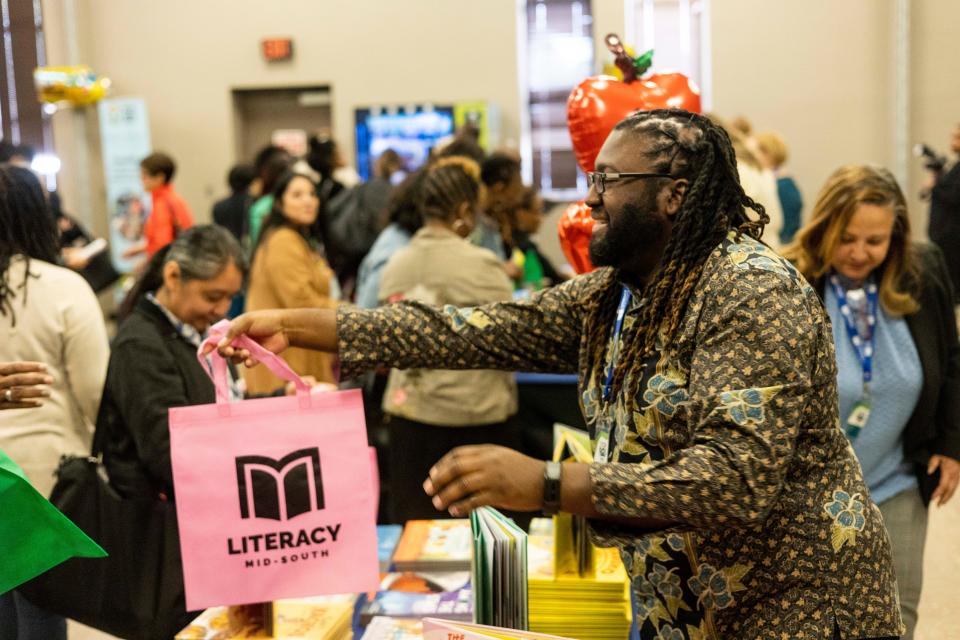 Literacy Mid-South tutor Jay Demoir can be seen passing out books and bags after the Memphis-Shelby County Schools and Literacy Mid-South Partnership Ceremony on Thursday, October 19, 2023 at the MSCS COE Auditorium in Memphis, Tenn.