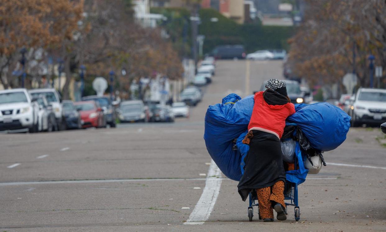 <span>An unhoused women moves her belongings after being evicted from a downtown street in San Diego, California, on 26 February 2024.</span><span>Photograph: Mike Blake/Reuters</span>